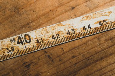 Çalışan ahşap bir masa üzerinde siyah numaraları ile eski paslı cetvel. vintage ölçüm bandı. endüstriyel arka plan