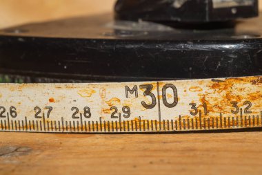 Çalışan ahşap bir masa üzerinde siyah numaraları ile eski paslı cetvel. vintage ölçüm bandı yakın. endüstriyel arka plan