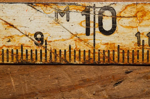 Régi rozsdás uralkodó fekete számok egy működő fából készült asztal. Vintage mérőszalag közelről. ipari háttér — Stock Fotó