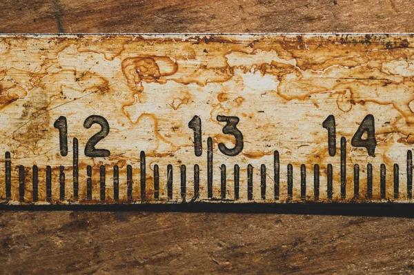 Çalışan ahşap bir masa üzerinde siyah numaraları ile eski paslı cetvel. vintage ölçüm bandı yakın. endüstriyel arka plan — Stok fotoğraf