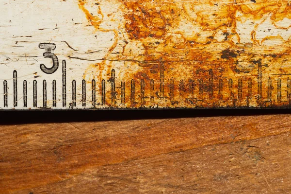 Стара іржава лінійка з чорними номерами на робочому дерев'яному столі. вінтажна вимірювальна стрічка крупним планом. промисловий фон — стокове фото