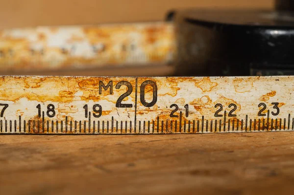 Régi rozsdás uralkodó fekete számok egy működő fából készült asztal. Vintage mérőszalag közelről. ipari háttér — Stock Fotó