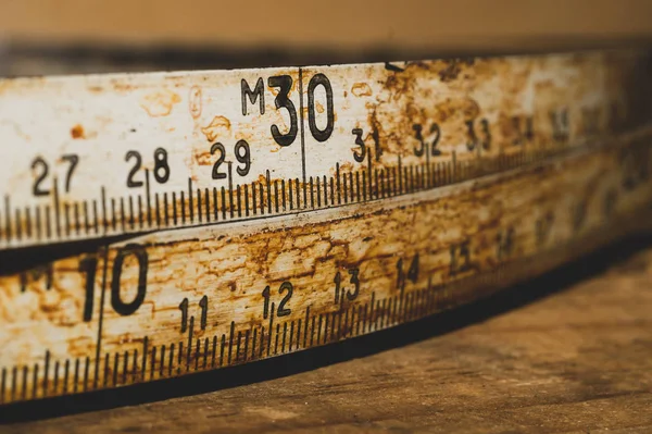 Çalışan ahşap bir masa üzerinde siyah numaraları ile eski paslı cetvel. vintage ölçüm bandı yakın. endüstriyel arka plan