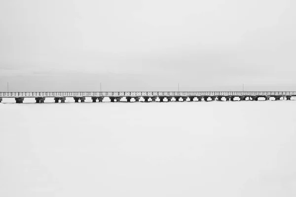 Pont sur le lac gelé. passerelle divisant l'horizon. image conceptuelle minimaliste. fond noir et blanc — Photo