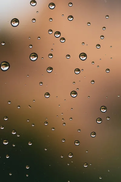 Gotas de lluvia en el cristal de la ventana se cierran. gotas de agua abstracto macro fondo — Foto de Stock
