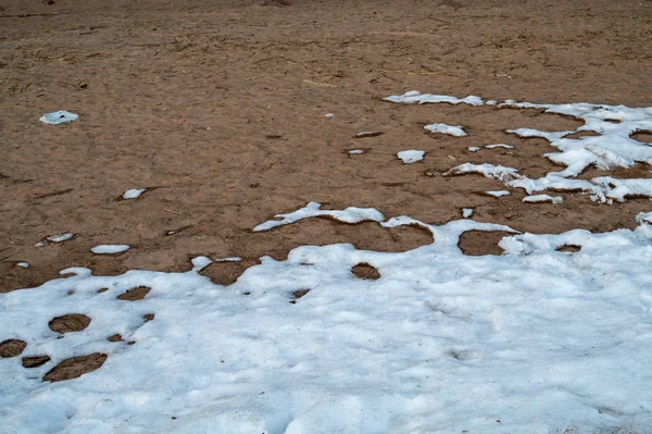 Arena cubierta de nieve. derretimiento de nieve en el suelo de heladas —  Fotos de Stock