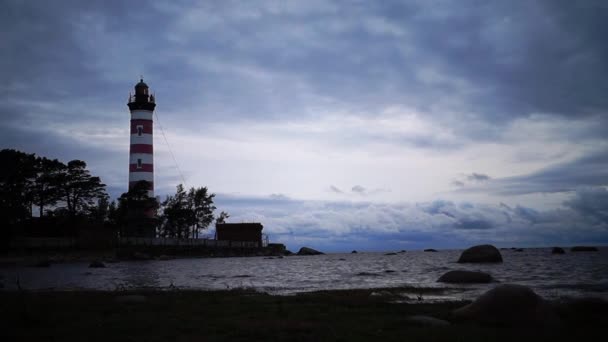 Le phare brille près du rivage au coucher du soleil. balise le soir