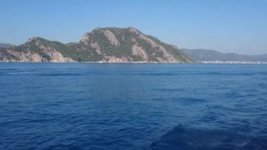 Mavi denizde hareket eden bir tekneden, dağ manzarasından görüntü
