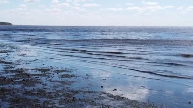 Deniz dalgaları kıyıya yavaş çekimde geliyor. Dalgalı su yüzeyi. Ufuk çizgisi olan deniz manzarası