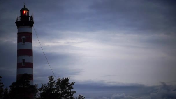 Le phare brille près du rivage au coucher du soleil. balise le soir