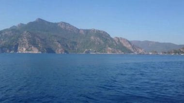 Mavi denizde hareket eden bir tekneden, dağ manzarası