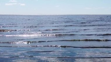 Deniz dalgaları kıyıya yavaş çekimde geliyor. Dalgalı su yüzeyi. Ufuk çizgisi olan deniz manzarası