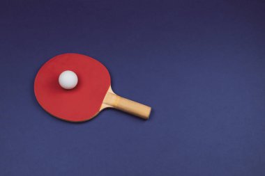 Kırmızı masa tenisi raketi ve renkli arka planda izole edilmiş bir top. Masa tenisi için spor malzemeleri. Boşluğu kopyala