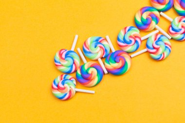 Lolipoplar yaklaşıyor. Sarı arka planda renkli şekerler. Şenlik dekorasyonu. Boşluğu kopyala