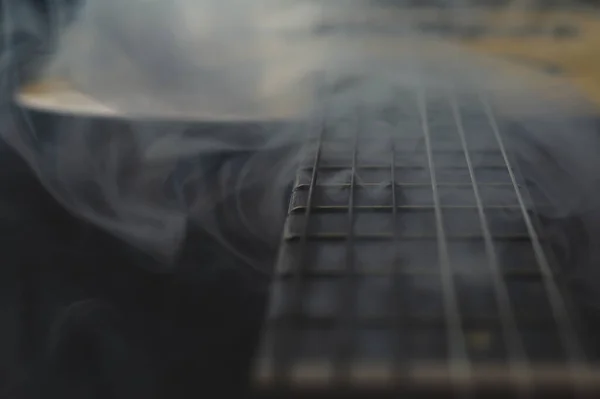 Acoustic guitar in smoke close up. musical instrument. strings on the guitar fretboard