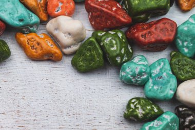Şeker parçacıkları. Renkli taşlar şeklinde tatlılar. Renkli şekerli ahşap bir arka plan. Boşluğu kopyala