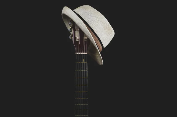 White hat hangs on the guitar fretboard. acoustic musical instrument. strings on the guitar neck close up