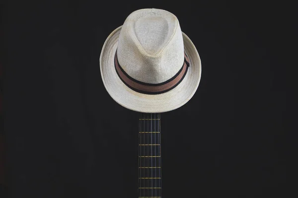 White hat hangs on the guitar fretboard. acoustic musical instrument. strings on the guitar neck close up