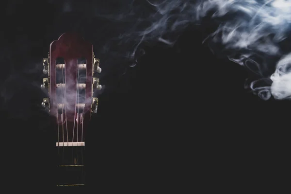 Guitar in smoke on the black background. acoustic musical instrument. strings on the guitar neck