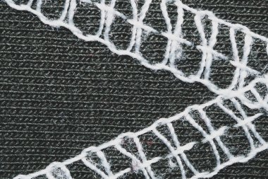 Siyah kumaşta beyaz dikişler. Tekstil malzemesine dikişler yakın.