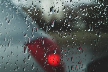 Camdaki yağmur damlaları. Arabanın penceresinden bak. Şiddetli yağmur. Şeffaf yüzeyde damlacıkları olan soyut arkaplan