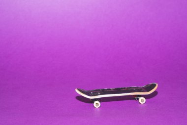 Mor arka planda küçük bir kaykay. Parmaklar için küçük bir paten. Klavye kapanıyor. Boşluğu kopyala