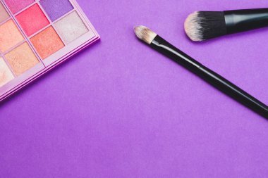 Mor arka planda pudralı makyaj fırçaları. çeşitli kozmetik fırçalar. cilt bakım aksesuarları