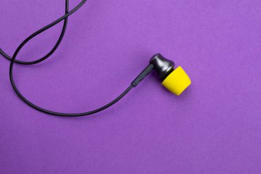 Mor arka planda sarı kulak minderi olan kulaklık. Kulaklıklar. ses ekipmanları
