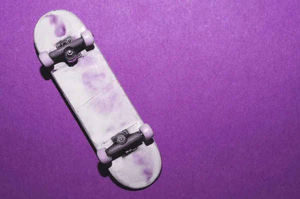 紫の背景に小さなスケートボード 指のための小さなスケート 指板を閉めろ コピースペース — ストック写真