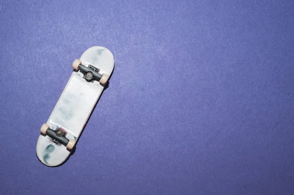 青い背景に小さなスケートボード 指のための小さなスケート 指板を閉めろ コピースペース — ストック写真