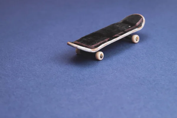 Small skateboard on blue background. tiny skate for fingers. fingerboard close up. copy space