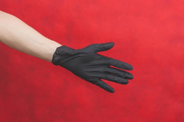 Ręka Rękawicy Ochronnej Czerwonym Tle Gestykulująca Dłoń Czarnej Rękawicy Medycznej — Zdjęcie stockowe