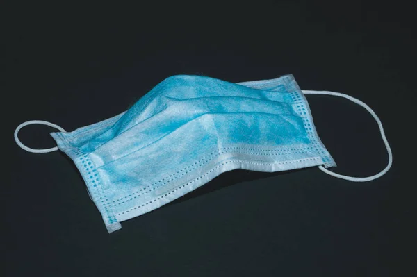 Siyah arka planda tek kullanımlık mavi maske. Koronavirüs ve solunum hastalıklarına karşı önleyici önlemler. tıbbi solunum bandajı