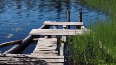 Göl kıyısındaki ahşap iskele. Görüntü aşağıdan yukarıya hareket eder. Yaz günü. yavaş çekim