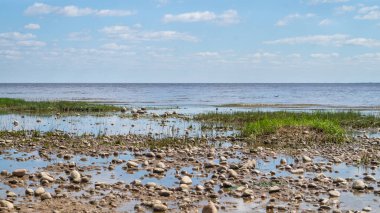 Denizin kıyısında. Ufuk çizgisi olan deniz manzarası. Bulutlu gökyüzü. Çakıl taşlı alüvyon kıyısı. su yüzeyi