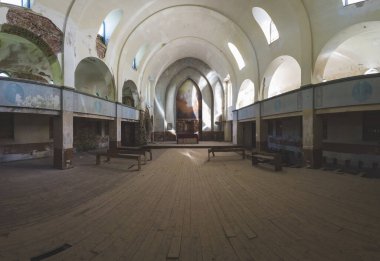 Terk edilmiş eski bir kilisede. Eski bir dini yapı. Sıralar ve sunaklar. Ahşap haç köşede duruyor.