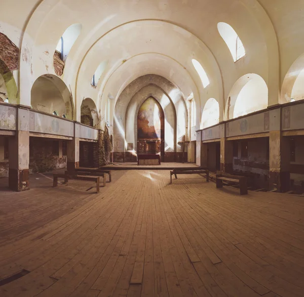 Inside an old abandoned church. ancient interior of religious building. benches and altar. wooden cross stands in the corner