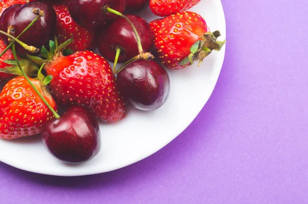 Cherries and strawberries on the white plate