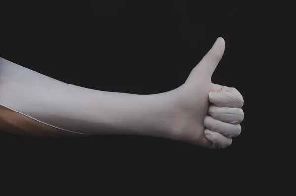 交上白色的医疗手套显示大拇指在黑色的背景上 — 图库照片