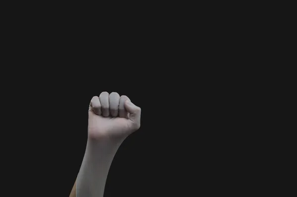 Hand in medical glove is clenched into a fist. gesturing hand in white protective glove on a black background