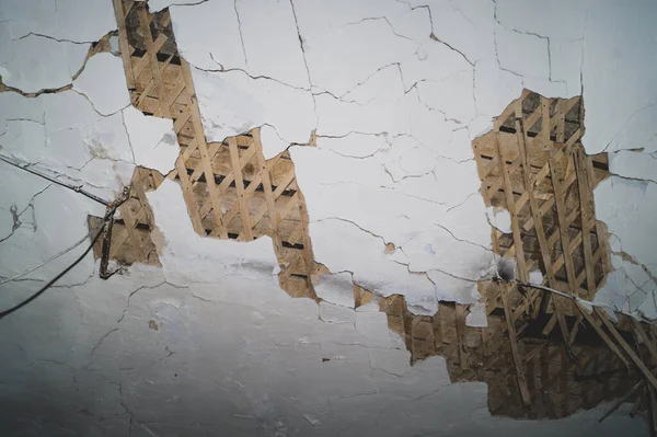 Dilapidated ceiling of an old house. damaged wall with a hole with timber frame. abstract background of ruined surface