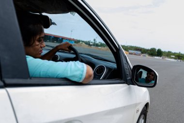 Kadın sürücü, açık bir günde kentsel bir ortamda çalışırken direksiyona odaklanır.