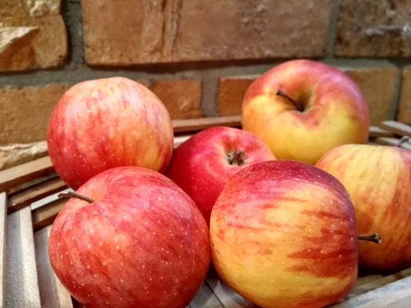Pommes rouges mûres sur table close up, sur fond de mur de briques — Photo