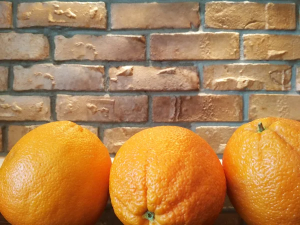 Fondo de frutas de naranja muchas frutas de naranja - fruta de naranja en el fondo de la pared de ladrillo — Foto de Stock