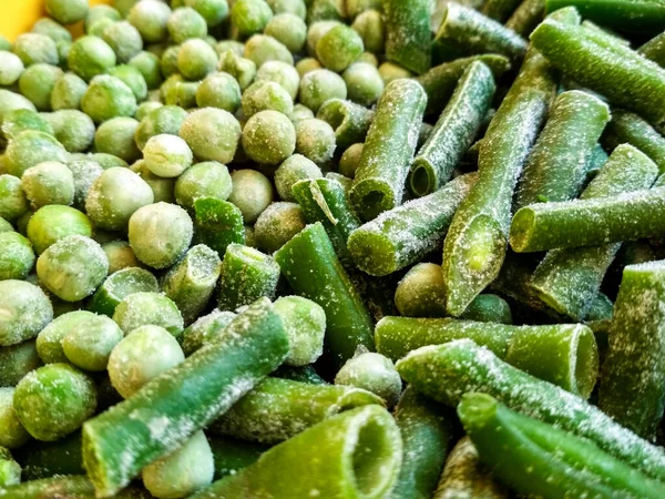 Groene bevroren bonen en erwten. Sluitende bevroren gesneden groene franse boon, haricot vert. Plantaardige voedselachtergrond. — Stockfoto