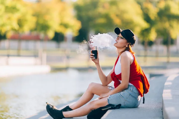 Bastante joven hipster mujer asiática en sombrero negro vape ecig, dispositivo de vapeo al atardecer. Imagen tonificada . —  Fotos de Stock