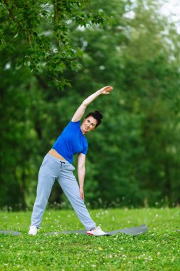 Parkta egzersiz kadın kıdemli. Yaşlı kadın fitness egzersizleri açık yapıyor. Heathy yaşam tarzı kavramı. Boşaltmak.