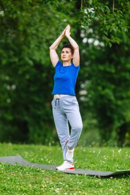 Yaşlı kadın parkta Yoga egzersiz yapmak. Kadın kıdemli pratik yoga açık. Heathy yaşam tarzı kavramı. Boşaltmak.
