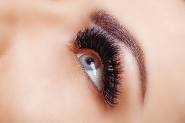 Kirpik uzatma yordamı. Kadın gözü ile uzun kirpiklerini. Yakın, seçici odak. Hollywood, Rus güç