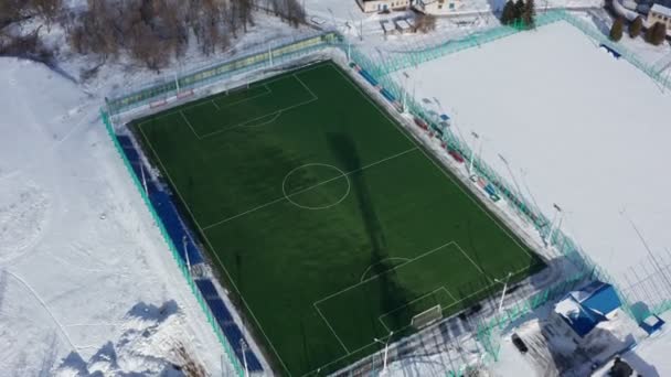 Аэросъемка любительского футбольного поля. Снимок современного футбольного поля с белой планировкой зимой. 4k кадров — стоковое видео
